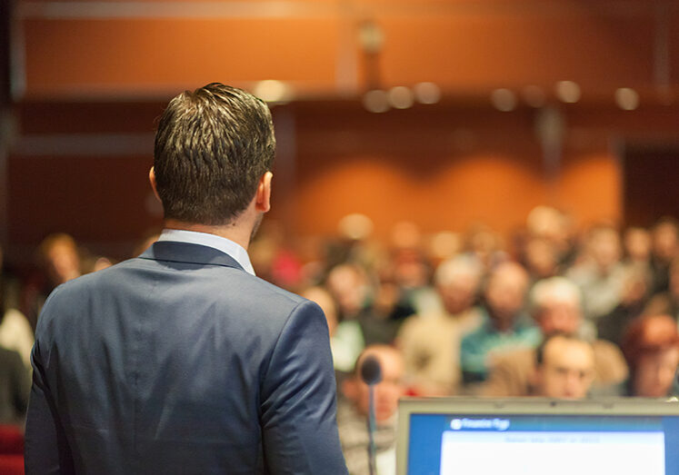 Speaker giving a talk on corporate Business Conference. Audience at the conference hall. Business and Entrepreneurship event.