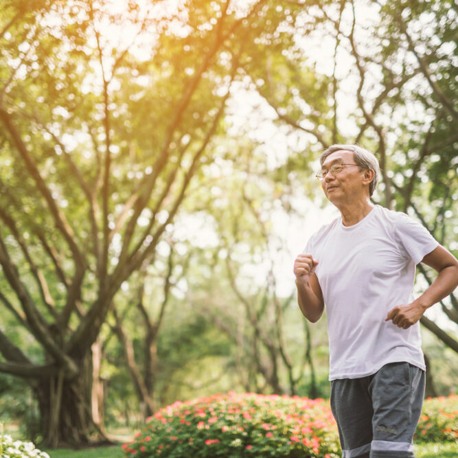 A male runs in a garden and forested area.