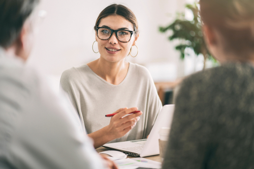 Female professional advisor sits across from clients to discuss life insurance.