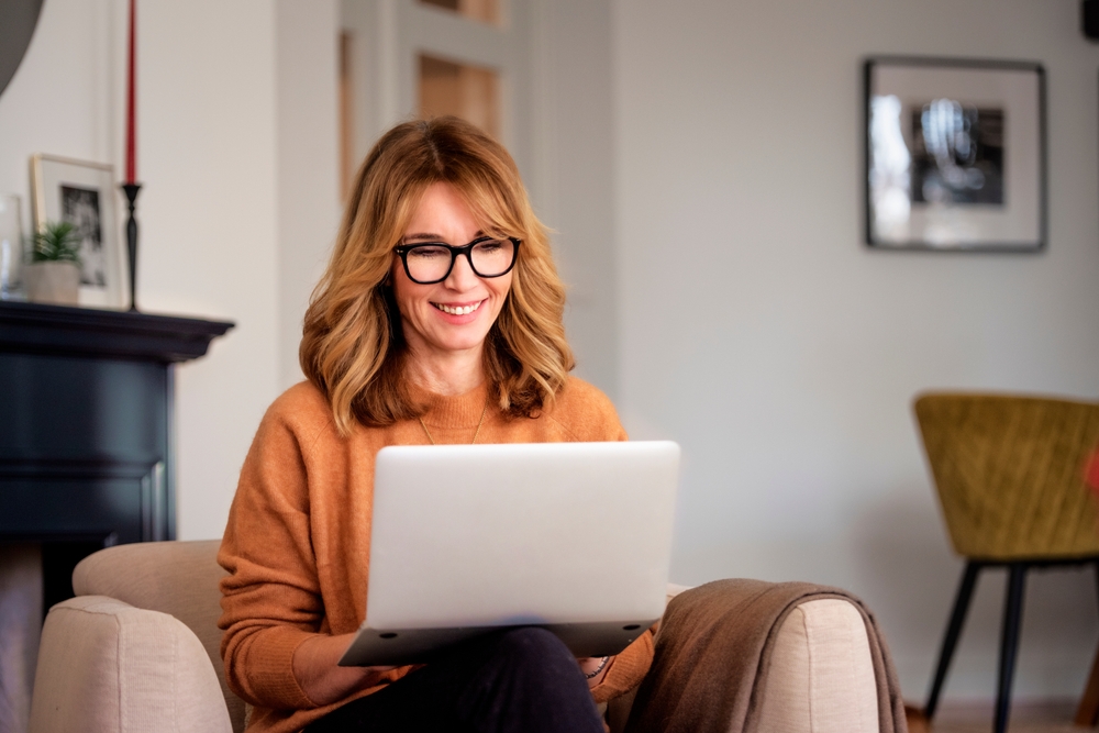 A middle-aged women uses her computer to learn about and fund her individual pension plan (IPP)